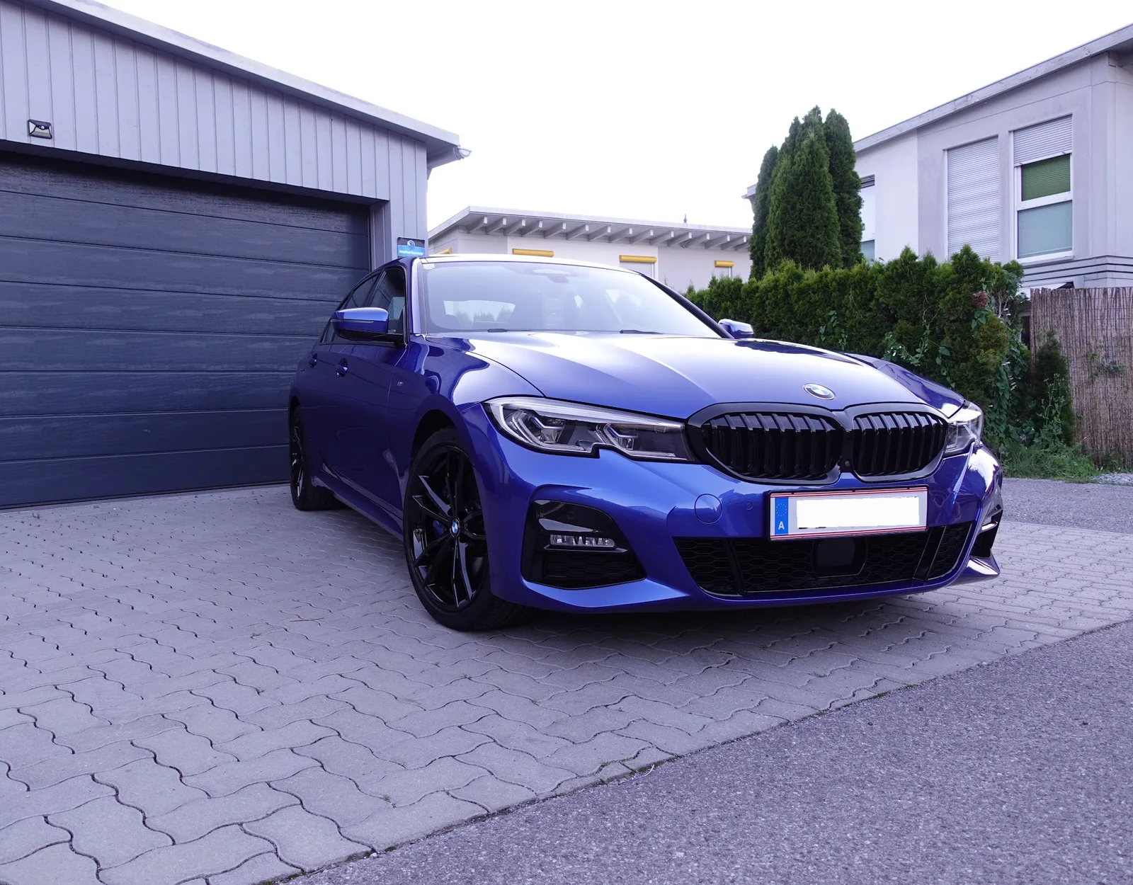 Blauer BMW 3er mit M-Paket im Freien vor dem Betrieb