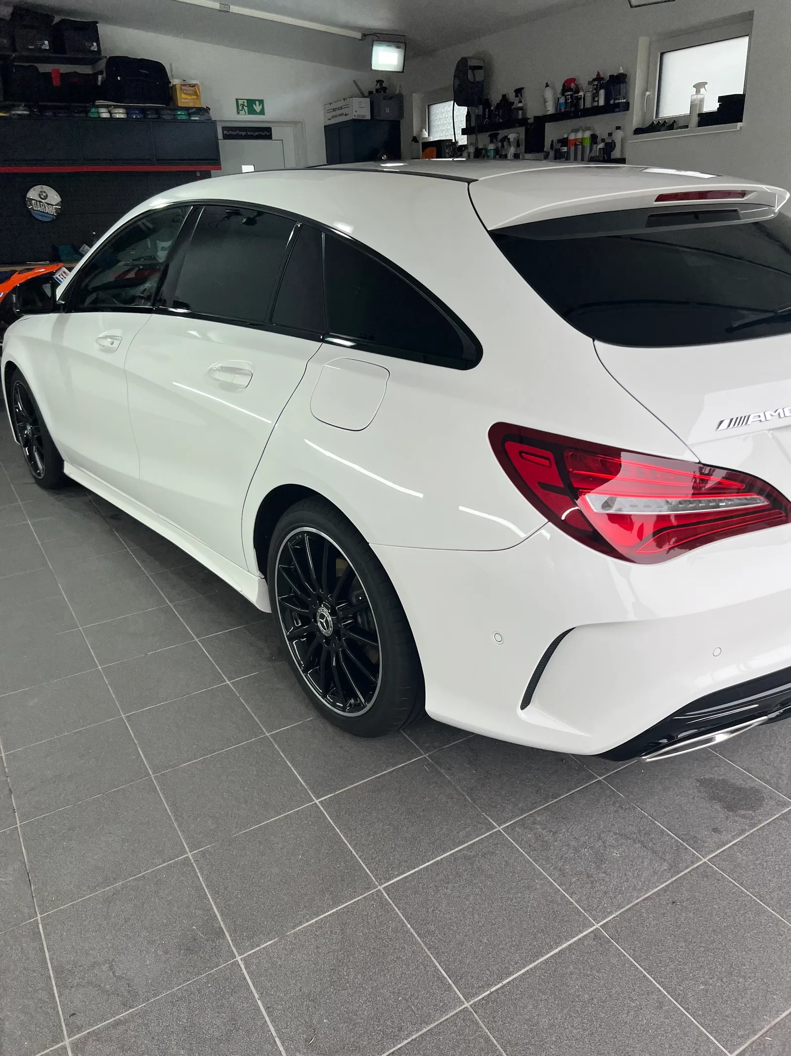 Weißer Mercedes CLA Shooting Brake in der Werkstatt, links im Hintergrund die Tür mit der Beschriftung Autopflege Mayerhofer